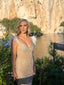 Woman in a sparkly dress standing in front of a scenic background with a lake and mountains.
